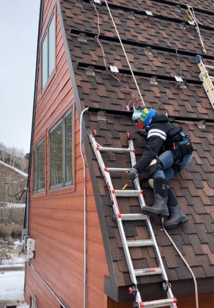 Future Proofing team member installing solar panel mounts on a Grand County rooftop